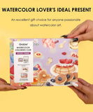 Hands holding Grabie Quarterly Watercolor Coloring Club box with dessert-themed watercolor art and gift message background