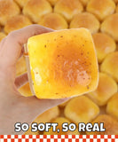 Hand holding a realistic yellow square squishy with speckles against a background of similar squishies Grabie Ultimate Stress Relief Squishy