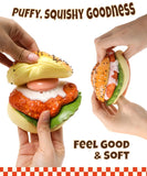 Two hands squeezing a chicken sandwich squishy toy with text Puffy Squishy Goodness Feel Good & Soft and the product name Grabie Ultimate Stress Relief Squishy