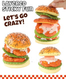 Hand stacking layers of a realistic chicken sandwich squishy toy labeled Grabie Ultimate Stress Relief Squishy for fun stress relief.