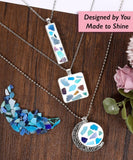 Create Your Own Healing Gem Pendant Kit with blue and purple gem pieces in silver pendants on wooden surface with flowers nearby