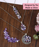 Create Your Own Healing Gem Pendant Kit showing three silver necklaces with purple and pink gem inlays on a wooden surface.